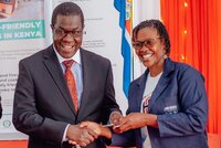 Opiyo Wandayi presents a key to a beneficiary during the handover of tuk-tuks to improved cookstove distributors