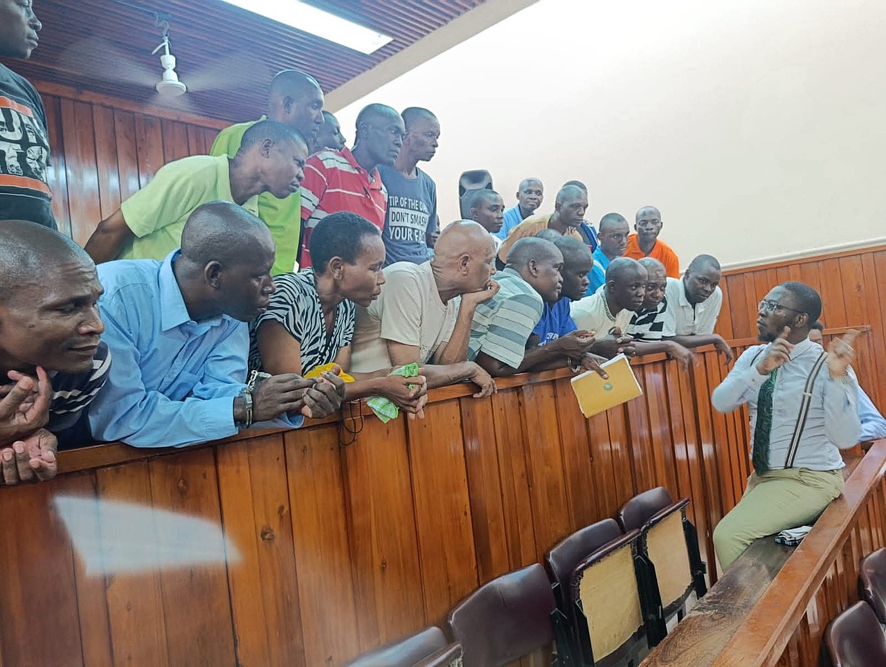 A Mombasa court official speaks with Paul Mackenzie and his co-accused in the Shakahola case