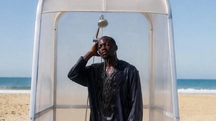 A man letting the water from a shower cascade over him as he escapes the intense heat of the scorching sun