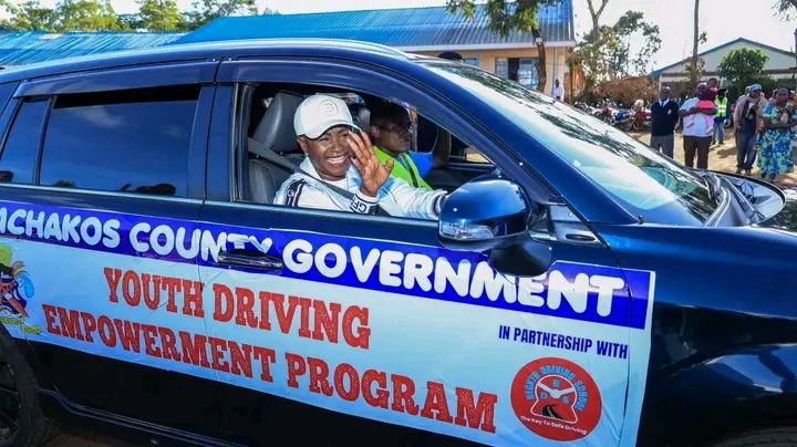 Machakos Governor Wavinya Ndeti greets youths while driving a car at Nguluni in Matungulu Sub-county during the launch of a county government programme to train 3,000 youths in motor vehicle driving and e-commerce